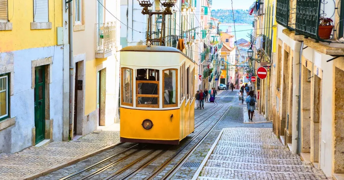 A classic yellow Lisbon tram climbing a cobbled street, Portugal